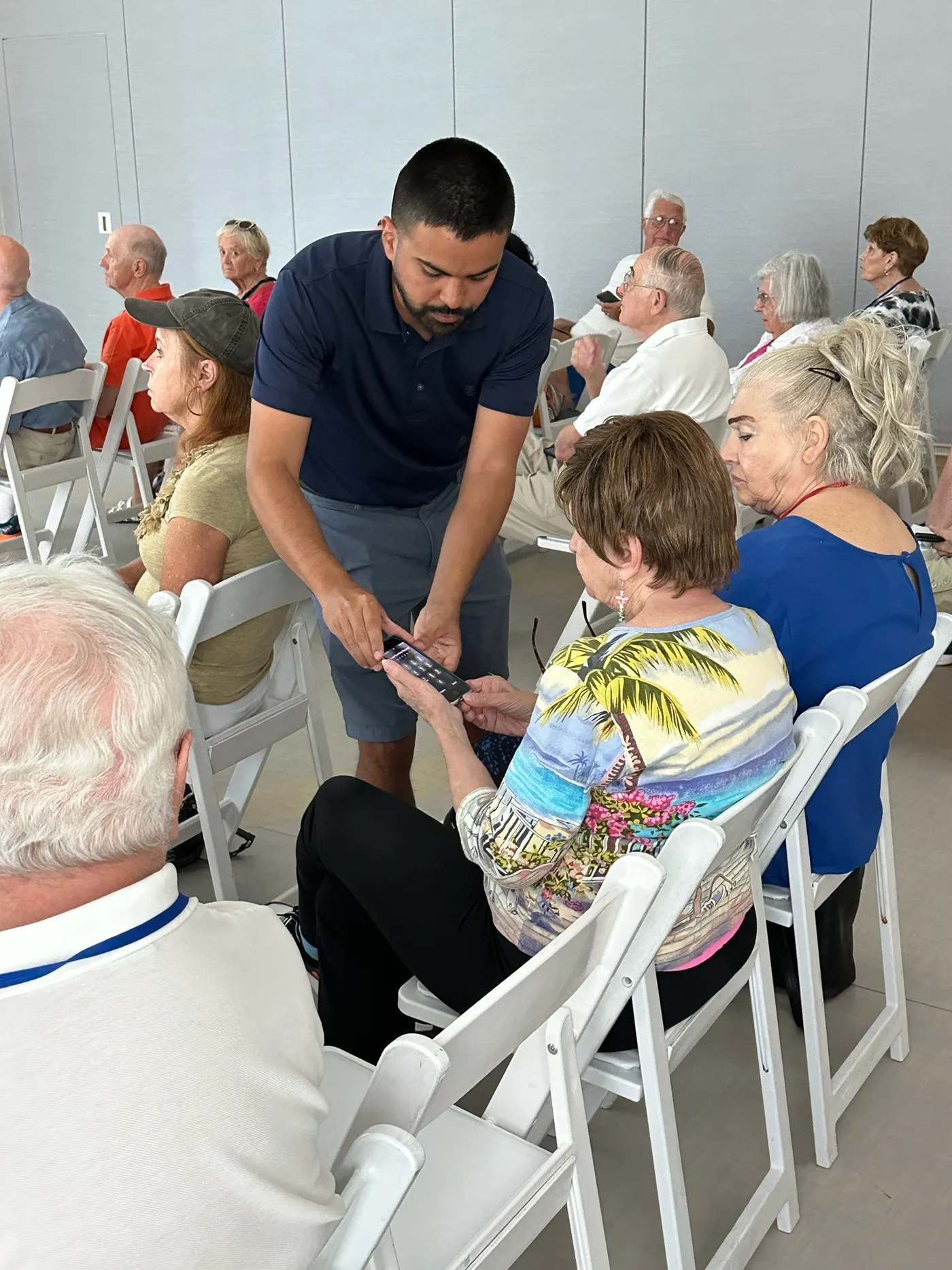 Erick Montano helping a seminar attendee with her phone while other seniors look on